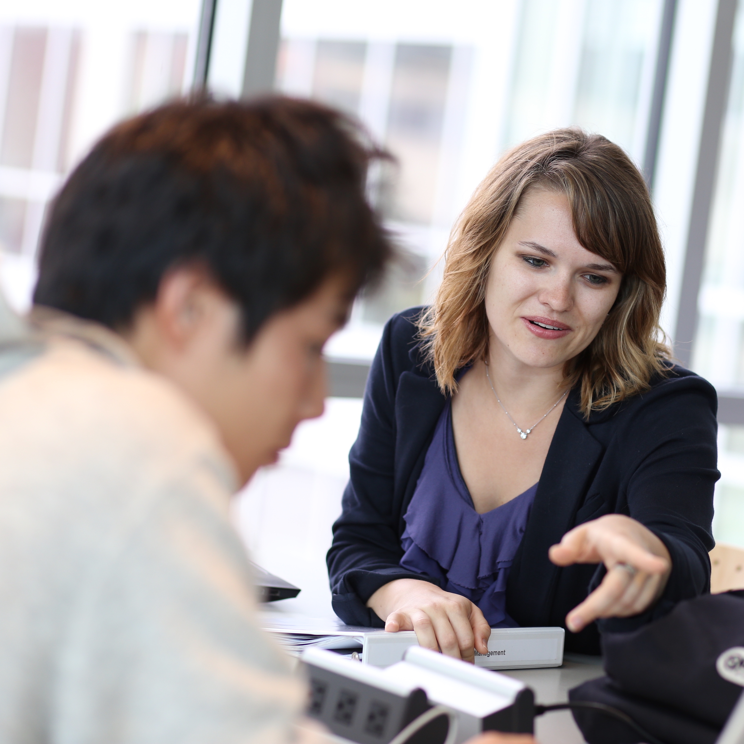 woman and man working together at a desk with windows in background