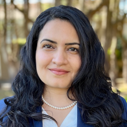 Venoo Kakar headshot, woman with long dark hair, wearing blue blazer and white blouse